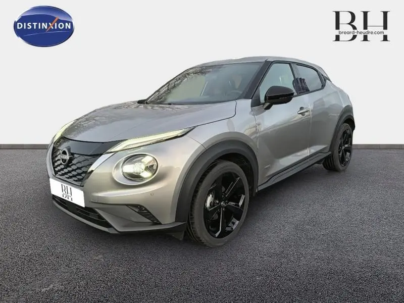 Nissan Juke 1.6 Hybrid Tekna 2025 gris perle métallisé, vue 3/4 avant avec jantes noires distinctives.