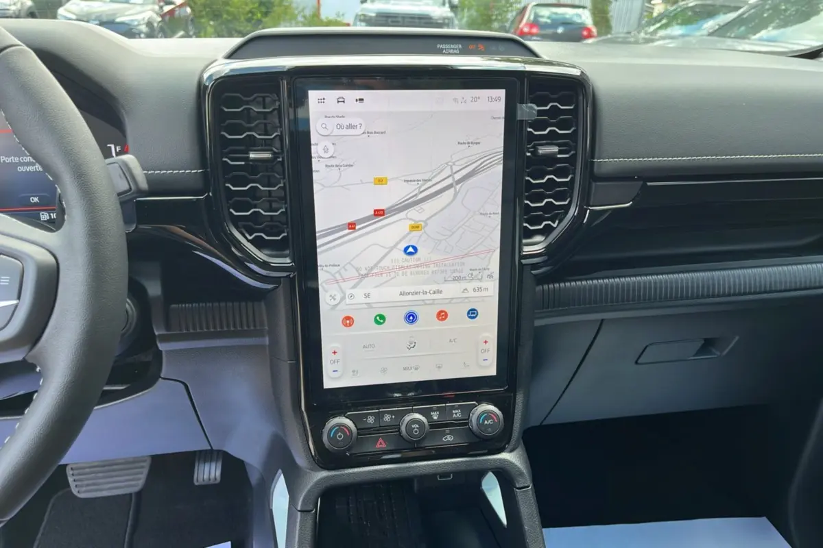 Vue intérieure centrée sur la console centrale tactile verticale du Ford Ranger gris zen avec volant cuir multifonctions partiel visible.