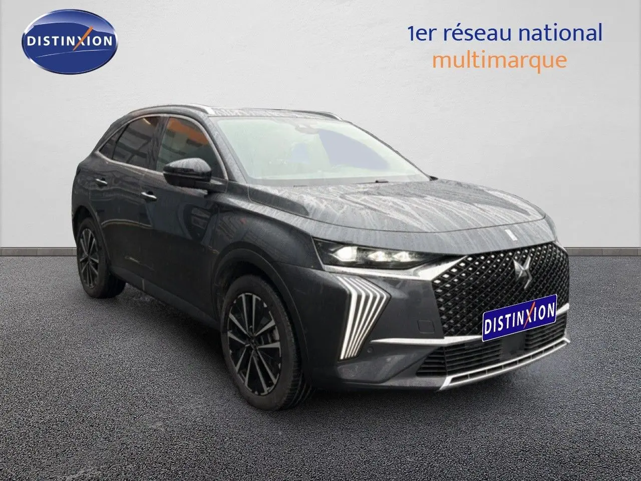 DS7 BlueHDi gris titane en 3/4 avant droit, avec calandre distinctive et feux LED en forme de flèche.