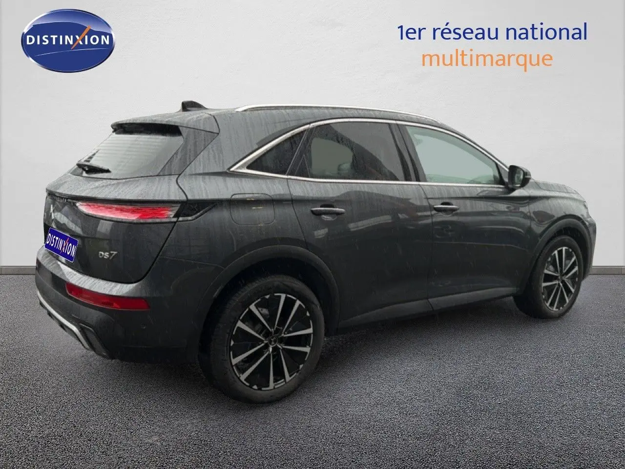 Vue 3/4 arrière droite d'un DS7 gris titane métal 2024 avec jantes noires bicolores et feux arrière LED fins.