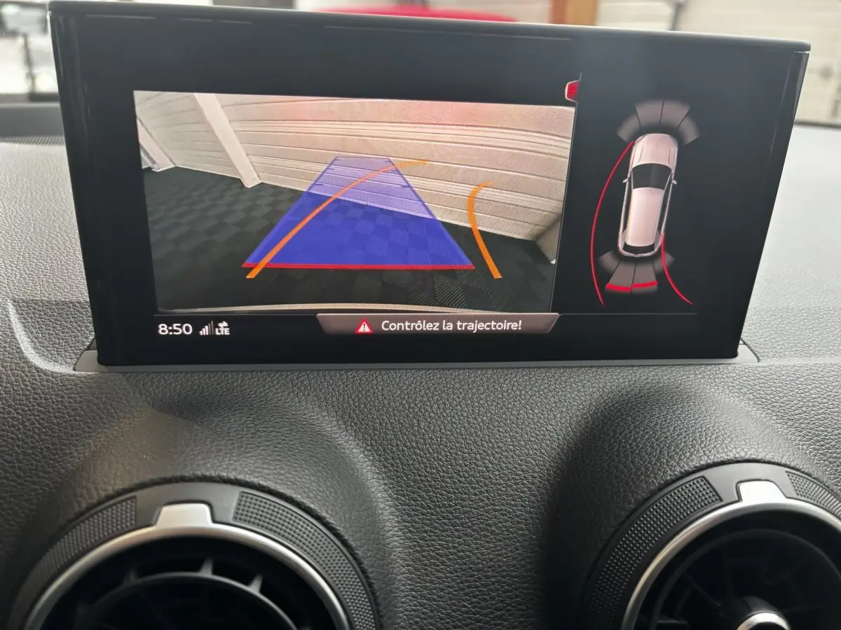 Écran central de l'Audi Q2 noir 2023 montrant l'aide au stationnement avec caméra arrière et guidage de trajectoire.