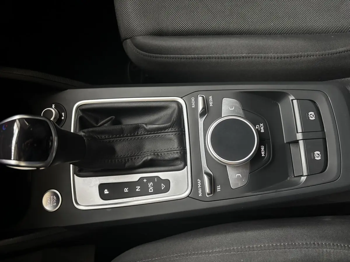 Vue rapprochée de la console centrale noire de l'Audi Q2 35 TFSI 150 S Tronic S Line avec levier de vitesses et commandes multimédia.
