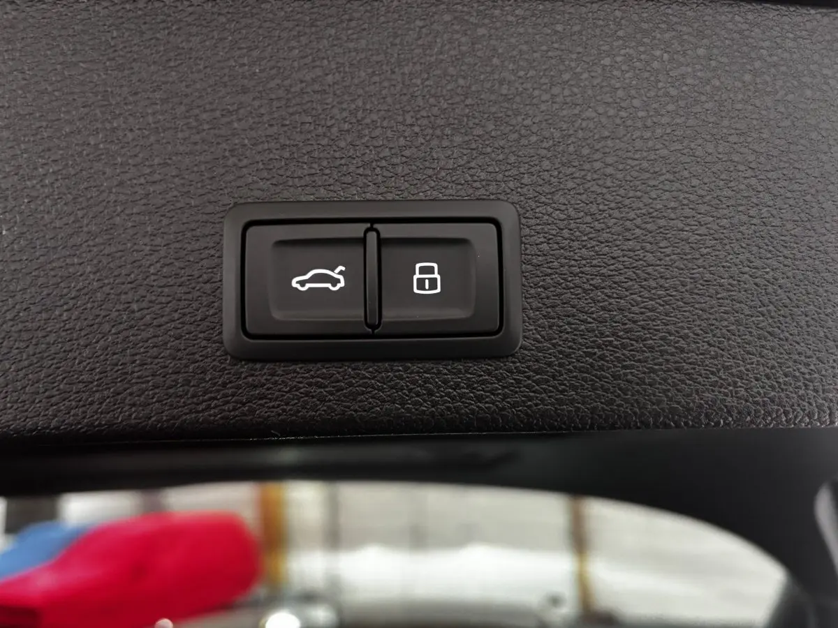 Gros plan sur les boutons d'ouverture de coffre et de verrouillage, intérieur noir texturé d'un Audi Q2 35 TFSI 2023.