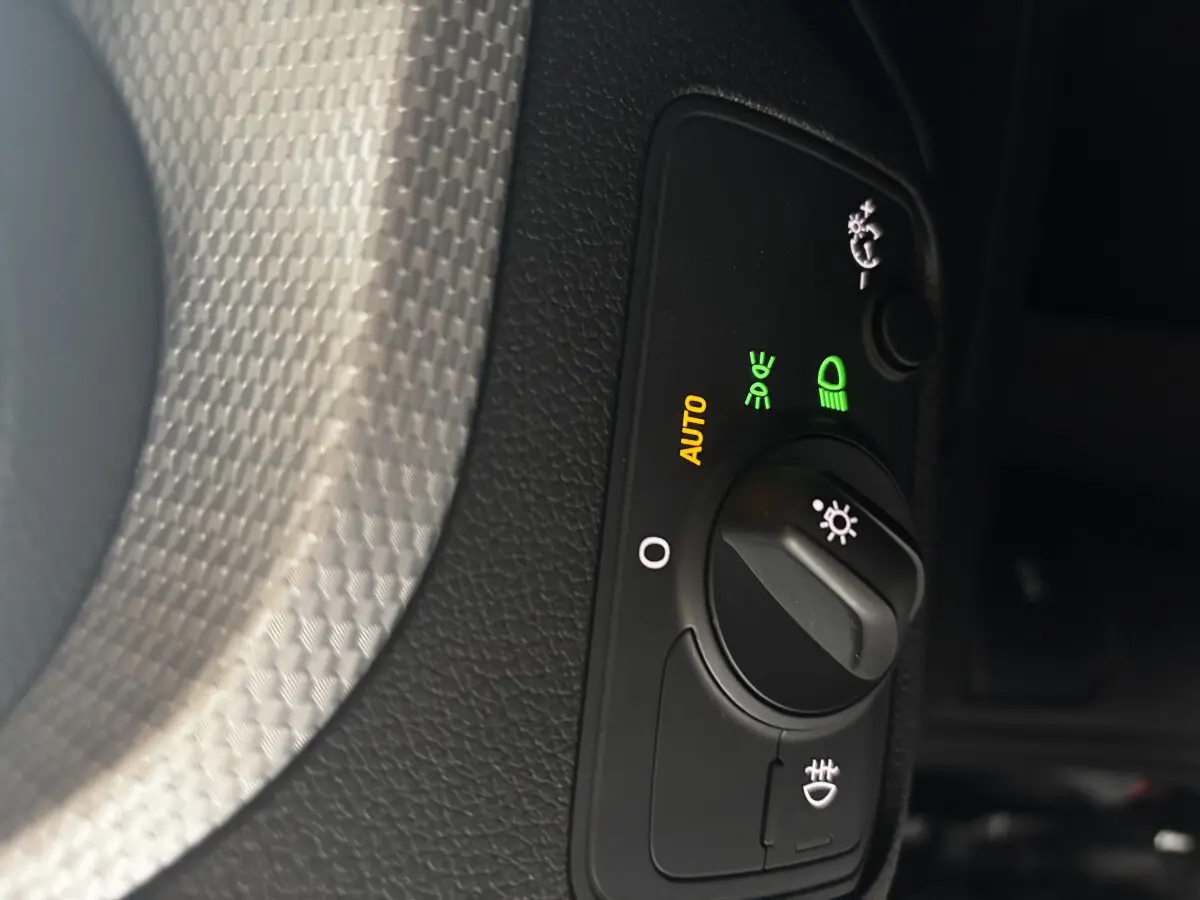 Gros plan sur la commande d’éclairage avec réglage automatique sur Audi Q2 noir 2023, finition S Line.