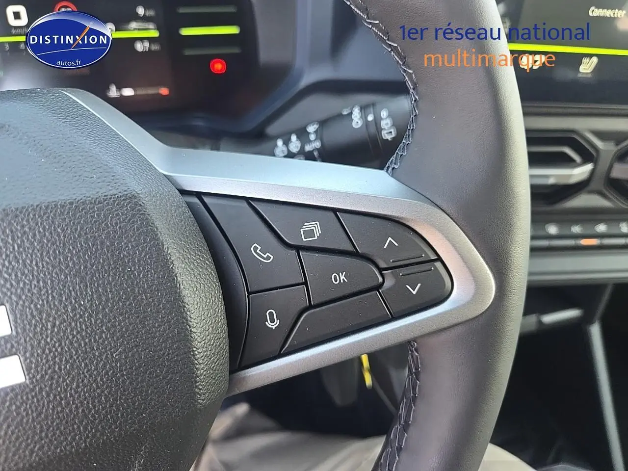 Gros plan sur les commandes multifonctions à droite du volant cuir du Dacia Duster vert kaki 2025, intérieur moderne.