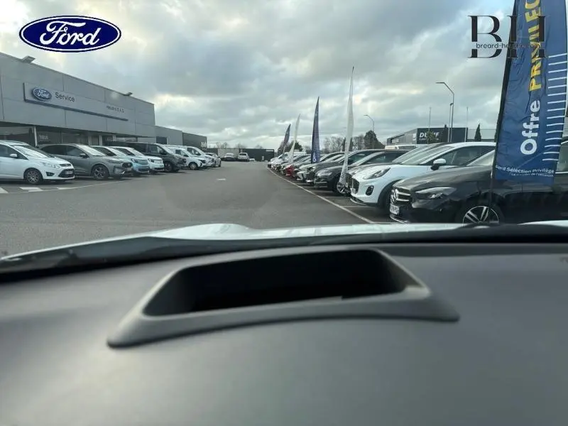 Vue depuis l'intérieur vers l'extérieur d'un parking de voitures, sans visibilité du Toyota Yaris Cross blanc Lunaire Nacré.