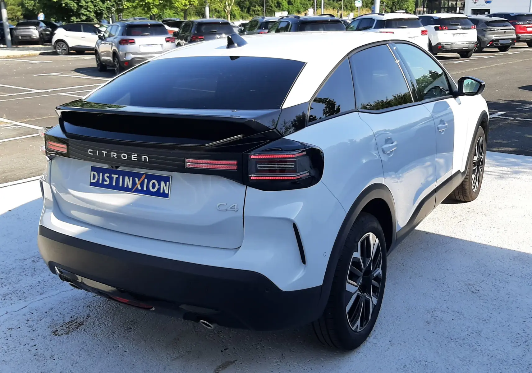 Vue 3/4 arrière droite d'une Citroën C4 blanche Okenite avec toit noir et feux arrière LED distinctifs.