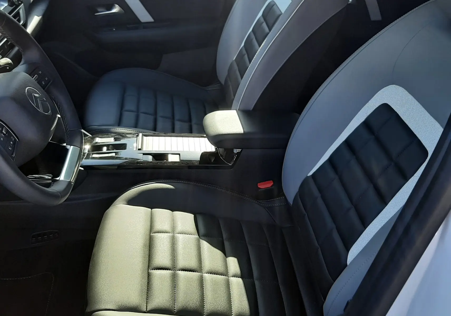 Vue intérieure côté gauche de la Citroën C4 1.2 Hybrid 145ch avec sièges bi-ton noirs et gris et console centrale brillante.