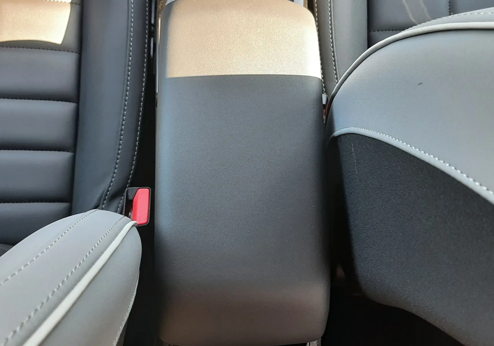 Vue plongeante sur l'accoudoir central bicolore noir et beige de l'intérieur de la Citroën C4 hybride 2025.