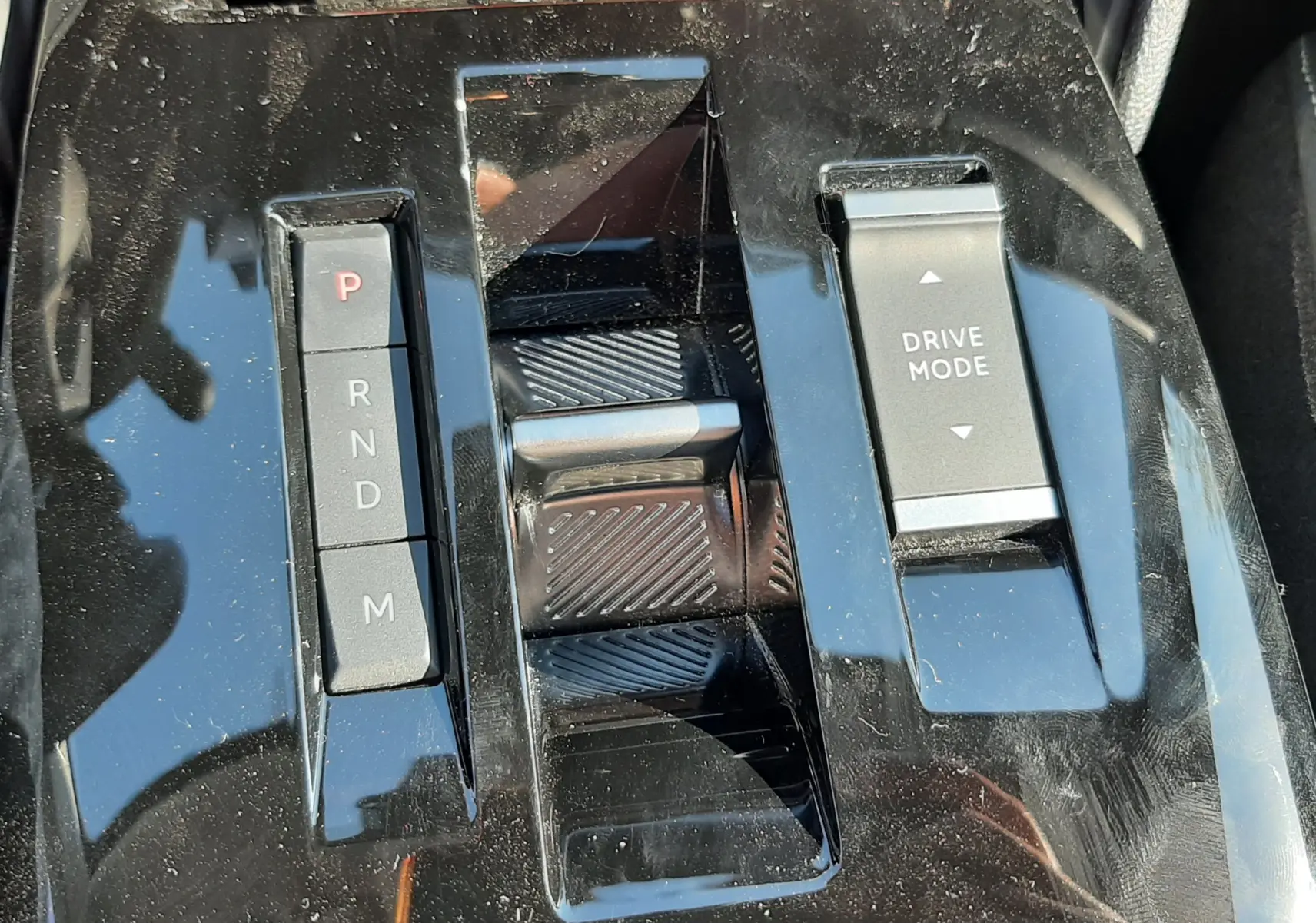 Gros plan sur la console centrale noire brillante de la Citroën C4 1.2 Hybrid 145ch avec sélecteur de boîte auto et bouton Drive Mode.