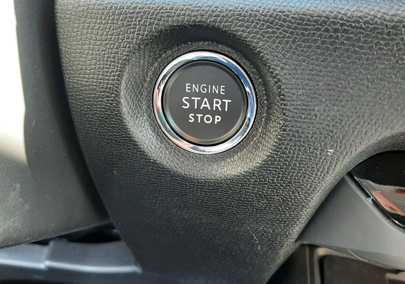 Gros plan sur le bouton moteur start/stop entouré de chrome dans l’habitacle noir texturé d’une Citroën C4 hybride 2025.