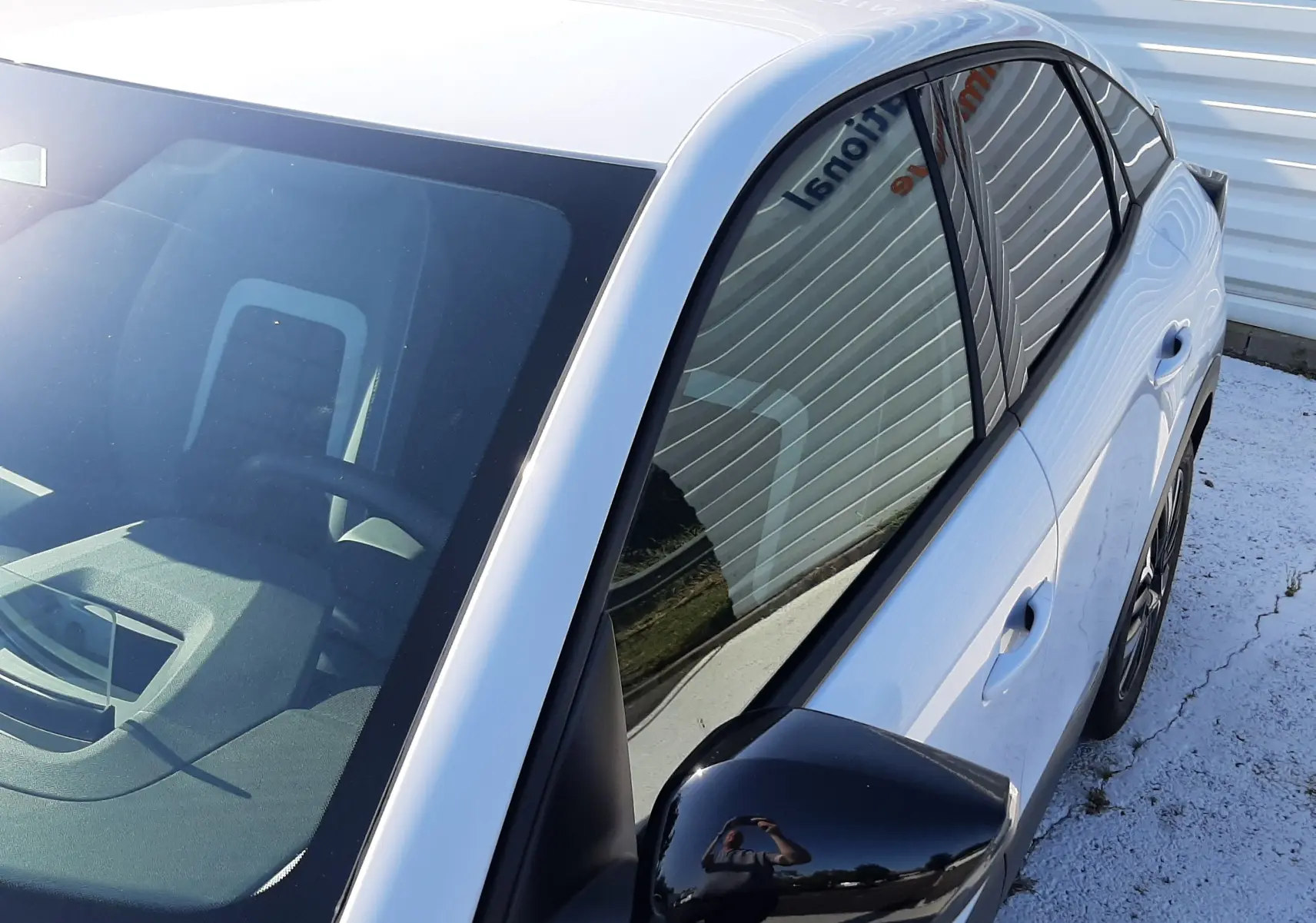 Vue 3/4 avant droit d'une Citroën C4 blanche Okenite avec rétroviseur noir brillant et vitres teintées.