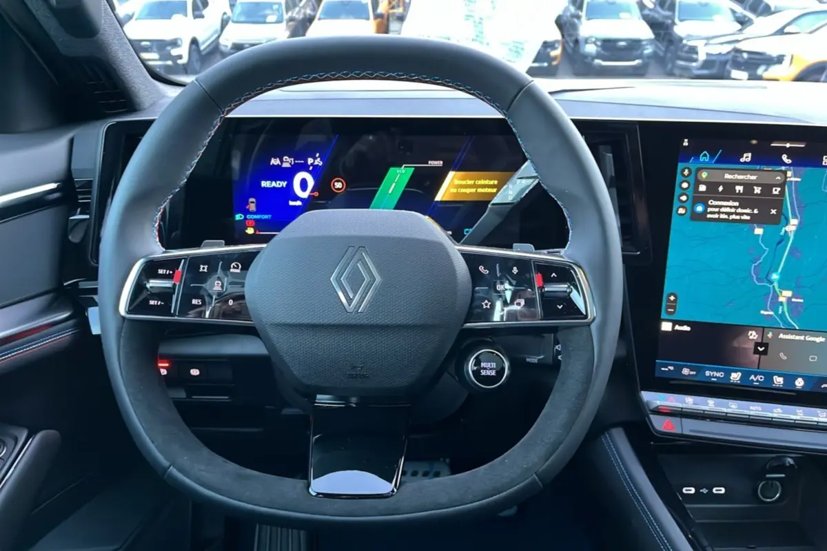 Vue frontale du volant cuir et alcantara avec logo Renault, tableau de bord numérique et écran tactile du Renault Rafale 2025.