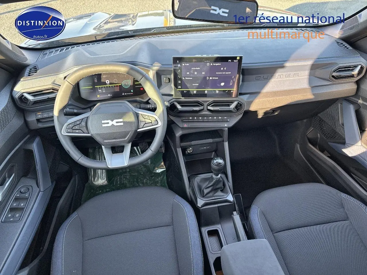 Vue intérieure frontale du tableau de bord et volant du Dacia Duster gris schiste, avec écran tactile et boîte manuelle.