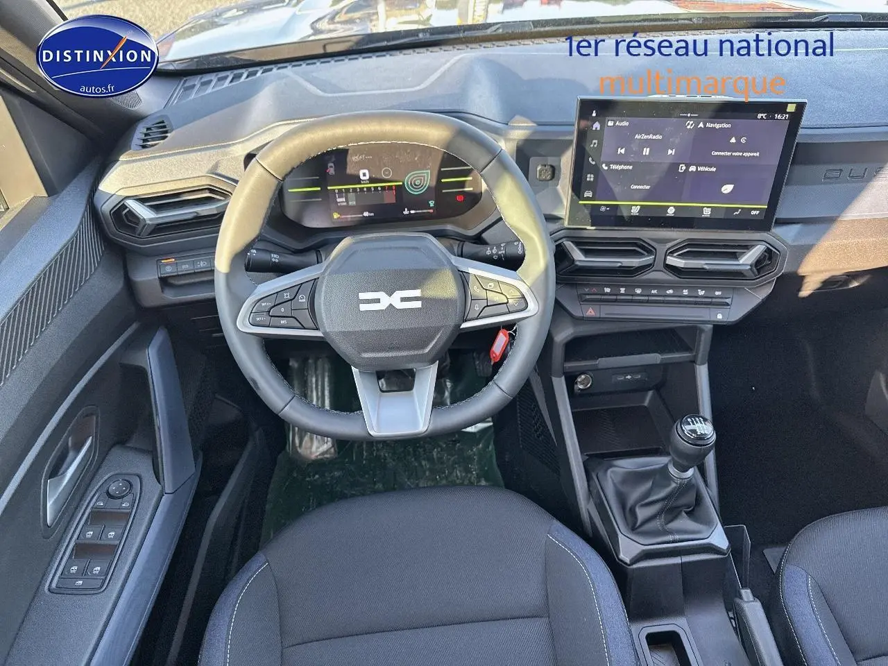 Vue intérieure avant du Dacia Duster 2025 gris schiste, volant multifonction et écran tactile central avec boîte manuelle.