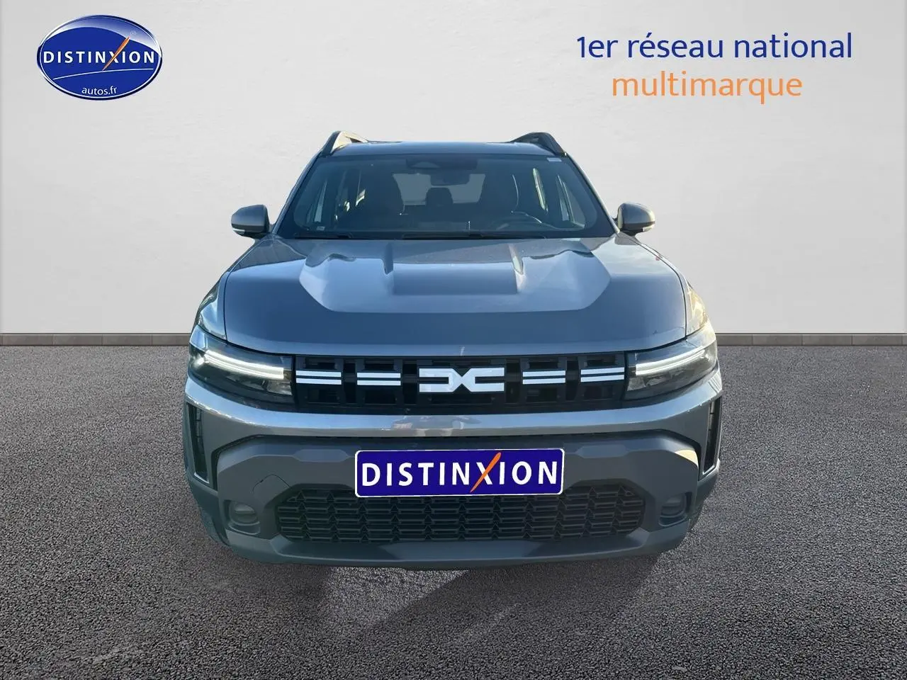 Vue avant d'un Dacia Duster gris schiste 2025 avec calandre distinctive et phares LED allumés.