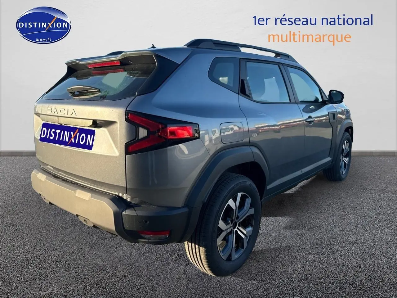 Vue 3/4 arrière droite du Dacia Duster gris schiste avec barres de toit et jantes alu distinctives.