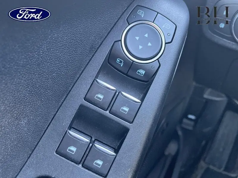 Gros plan sur les commandes des vitres électriques et rétroviseurs dans l'habitacle noir d'une Ford Fiesta gris lunaire 2020.