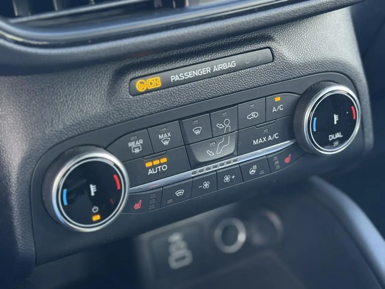 Gros plan sur la console de climatisation avec commandes chauffantes et affichage digital, intérieur noir du Ford Kuga.
