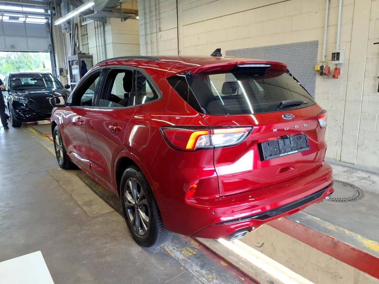 Vue 3/4 arrière droite du Ford Kuga rouge Lucifer 2024 avec jantes alliage et double sortie d’échappement ST-Line.