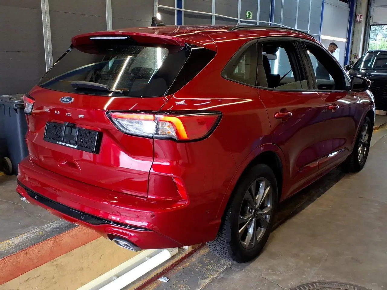 Vue 3/4 arrière droite du Ford Kuga rouge Lucifer 2024 avec double sortie d’échappement et jantes alliage 18 pouces.