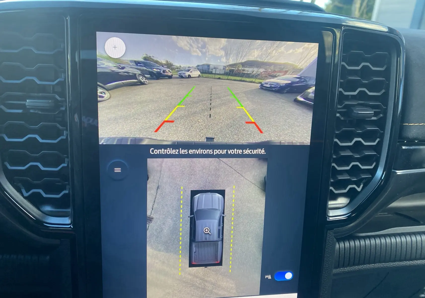 Écran intérieur montrant la caméra 360° et l’aide au stationnement du Ford Ranger gris carbone, vue arrière et vue aérienne.