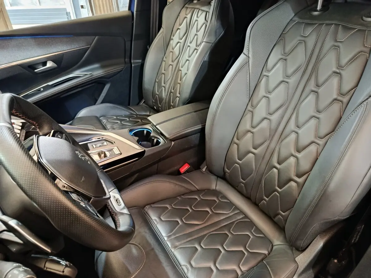 Vue intérieure côté conducteur du Peugeot 3008 GT Pack 1.6 Hybrid 225, sièges cuir noir avec surpiqûres géométriques.