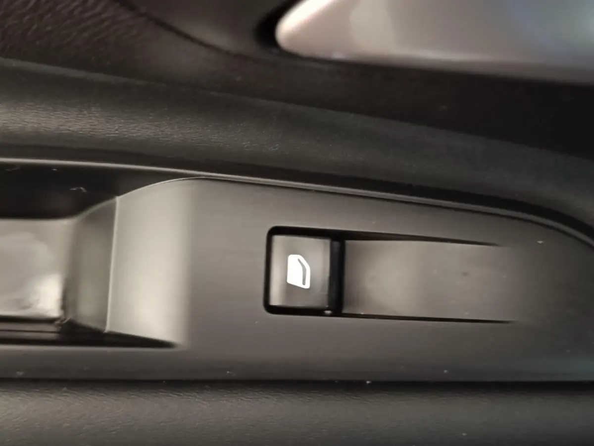 Gros plan sur le bouton de commande de lève-vitre côté conducteur du Peugeot 3008 hybride bleu 2020.