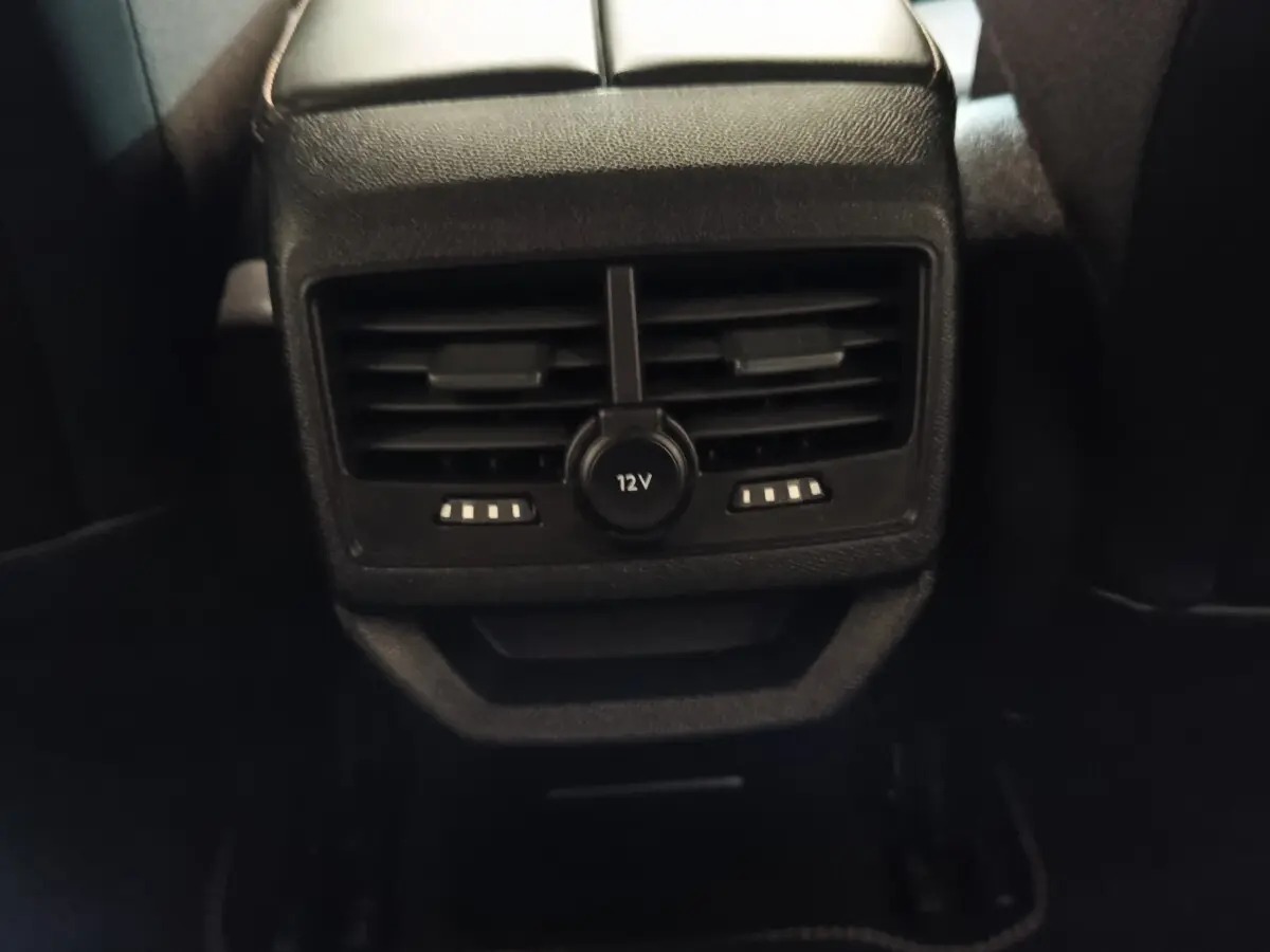 Gros plan sur la sortie d'air arrière avec prise 12V du Peugeot 3008 hybride bleu, intérieur sombre.