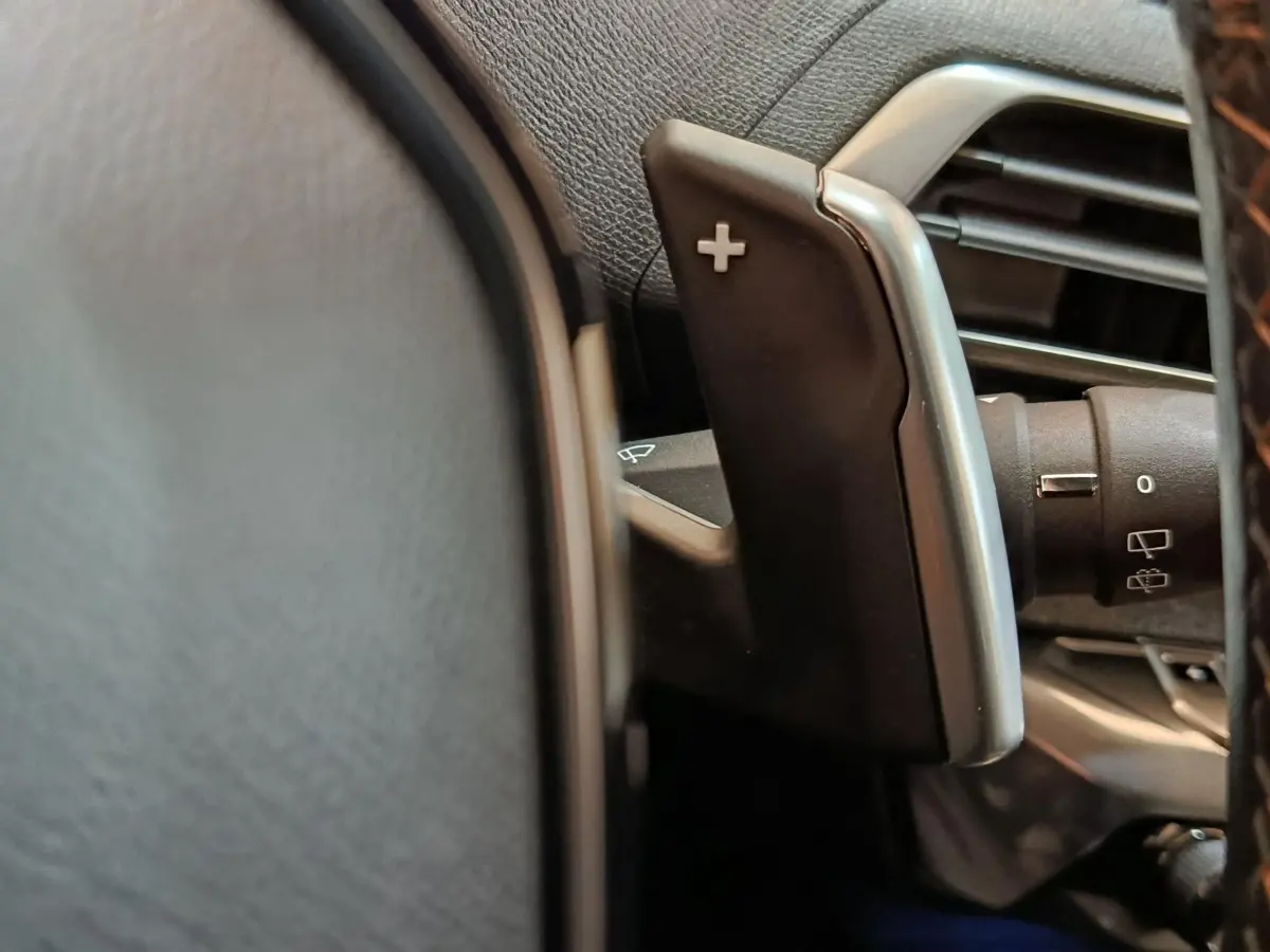 Gros plan sur la palette de changement de vitesse + au volant cuir du Peugeot 3008 bleu hybride rechargeable.