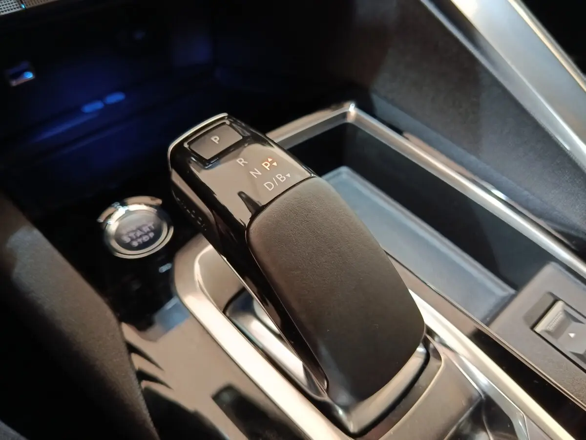 Gros plan sur le levier de vitesses automatique noir et gris du Peugeot 3008 hybride rechargeable, avec bouton start/stop visible.
