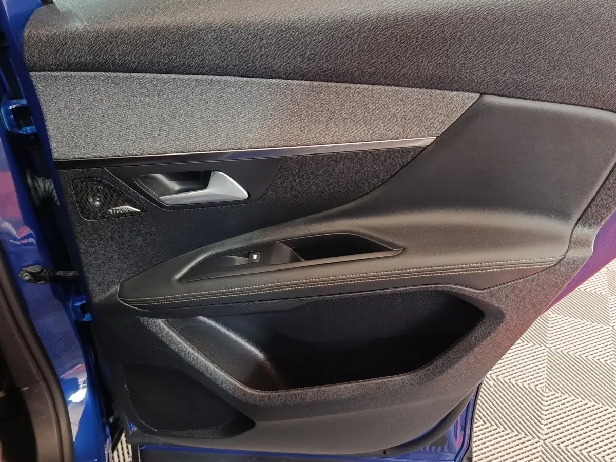 Vue intérieure côté gauche de la porte avant bleu du Peugeot 3008 hybride avec garniture tissu et cuir noir.