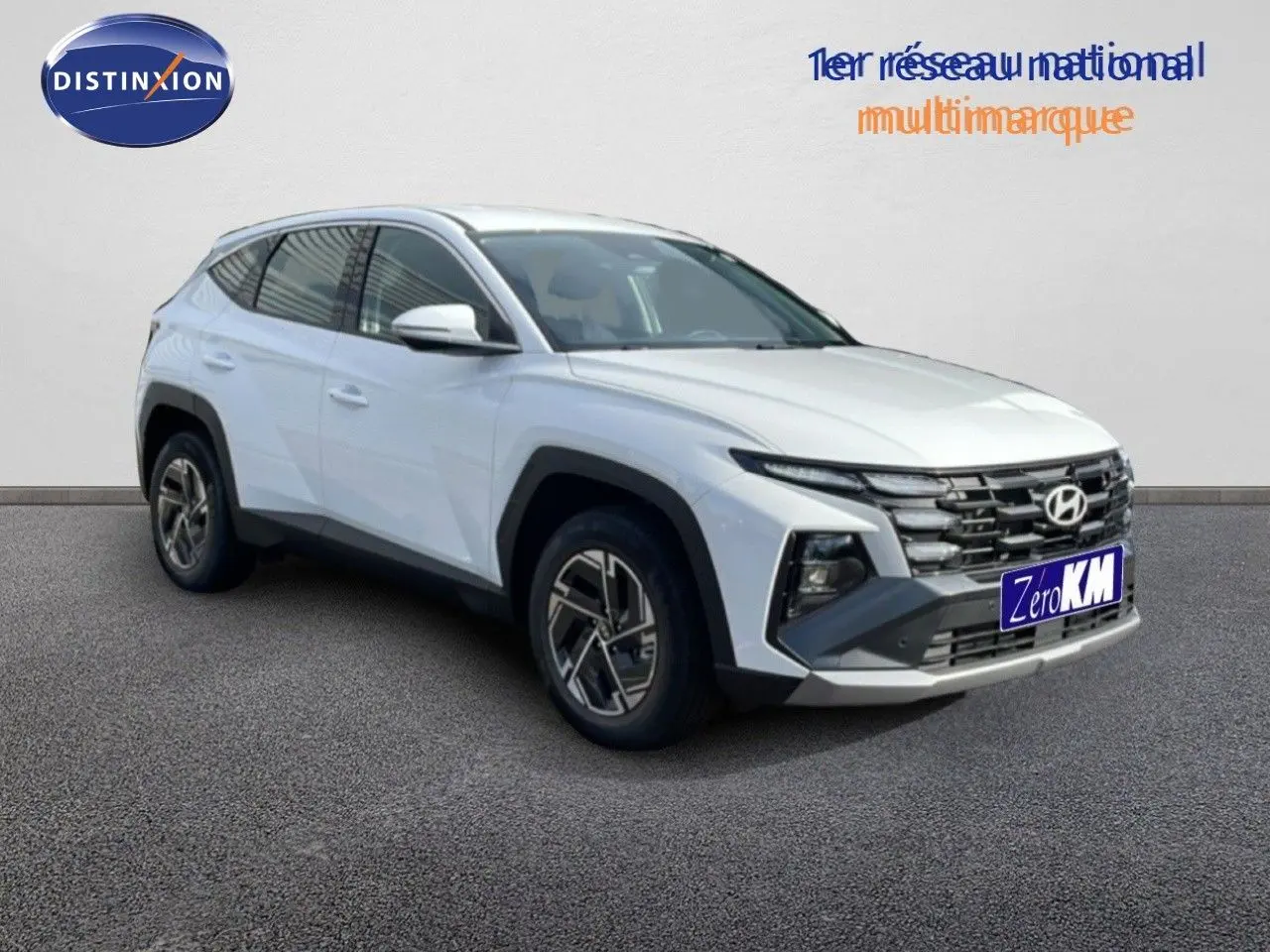Hyundai Tucson blanc Atlas en 3/4 avant droit, SUV hybride avec calandre distinctive et jantes bi-ton.