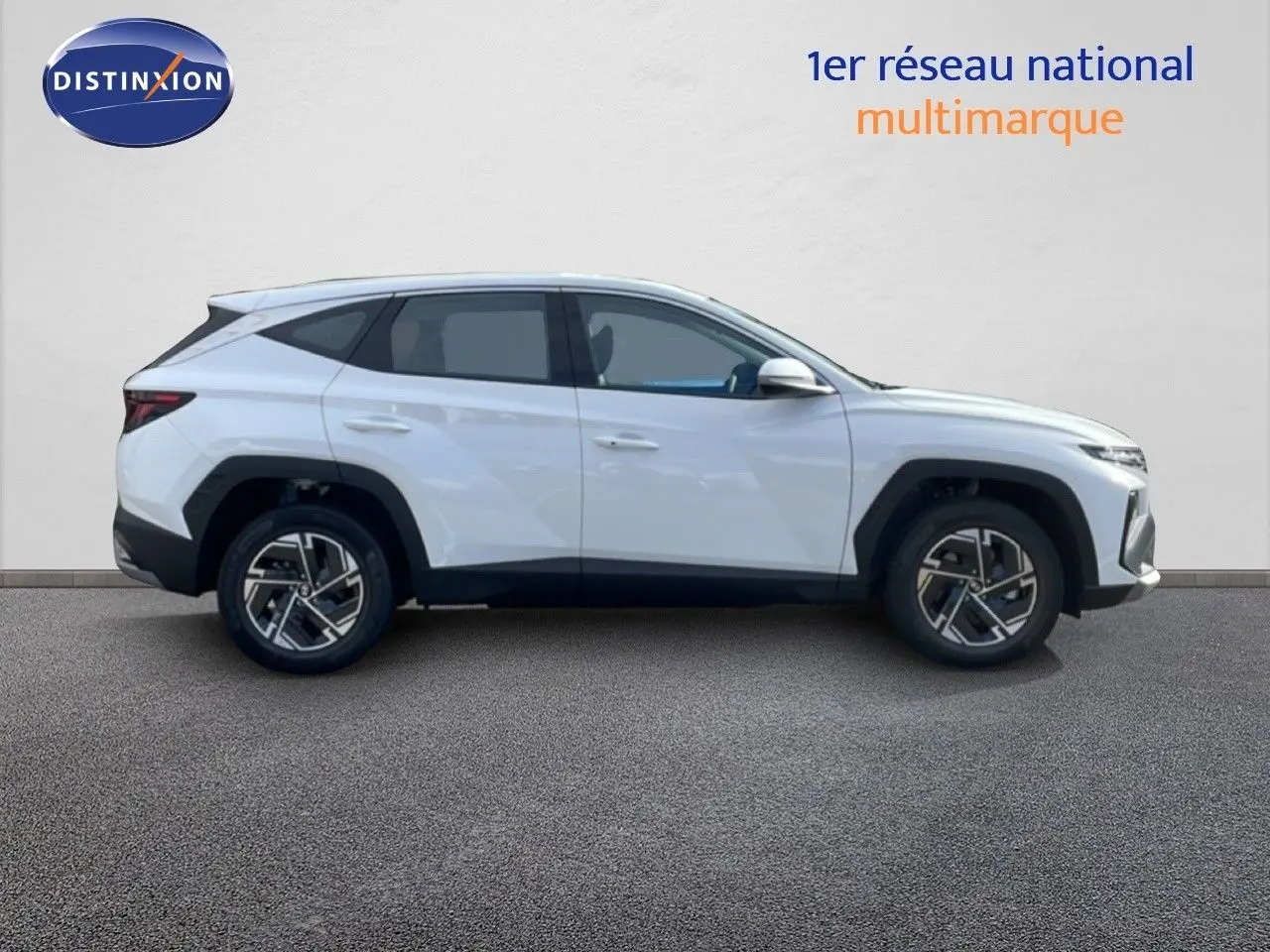Vue de profil côté gauche d'un Hyundai Tucson blanc Atlas 2026 avec jantes bi-ton et lignes anguleuses marquées.
