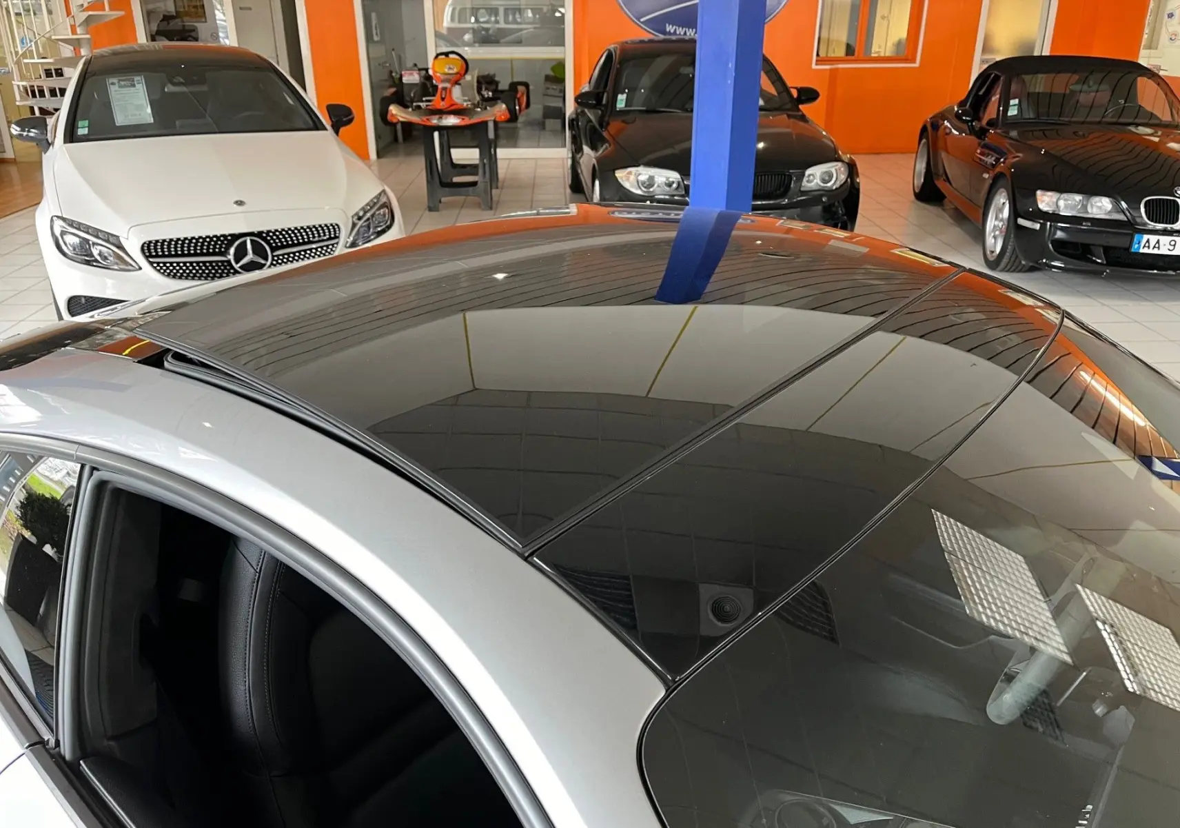 Vue plongeante sur le toit panoramique noir d'une Porsche 911 Carrera S argent GT en concession.