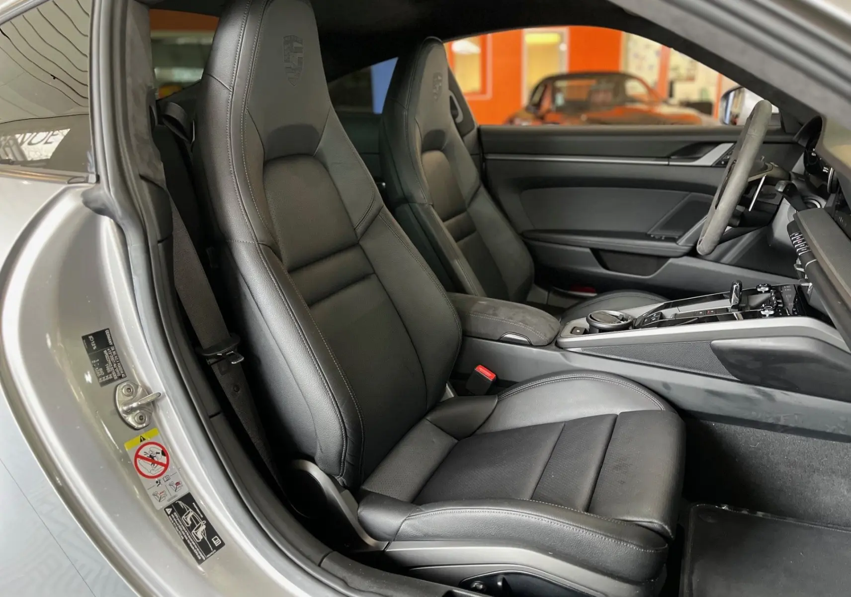 Intérieur de la Porsche 911 Carrera S 2019, vue côté conducteur, sièges cuir noir avec logo embossé et volant Alcantara.