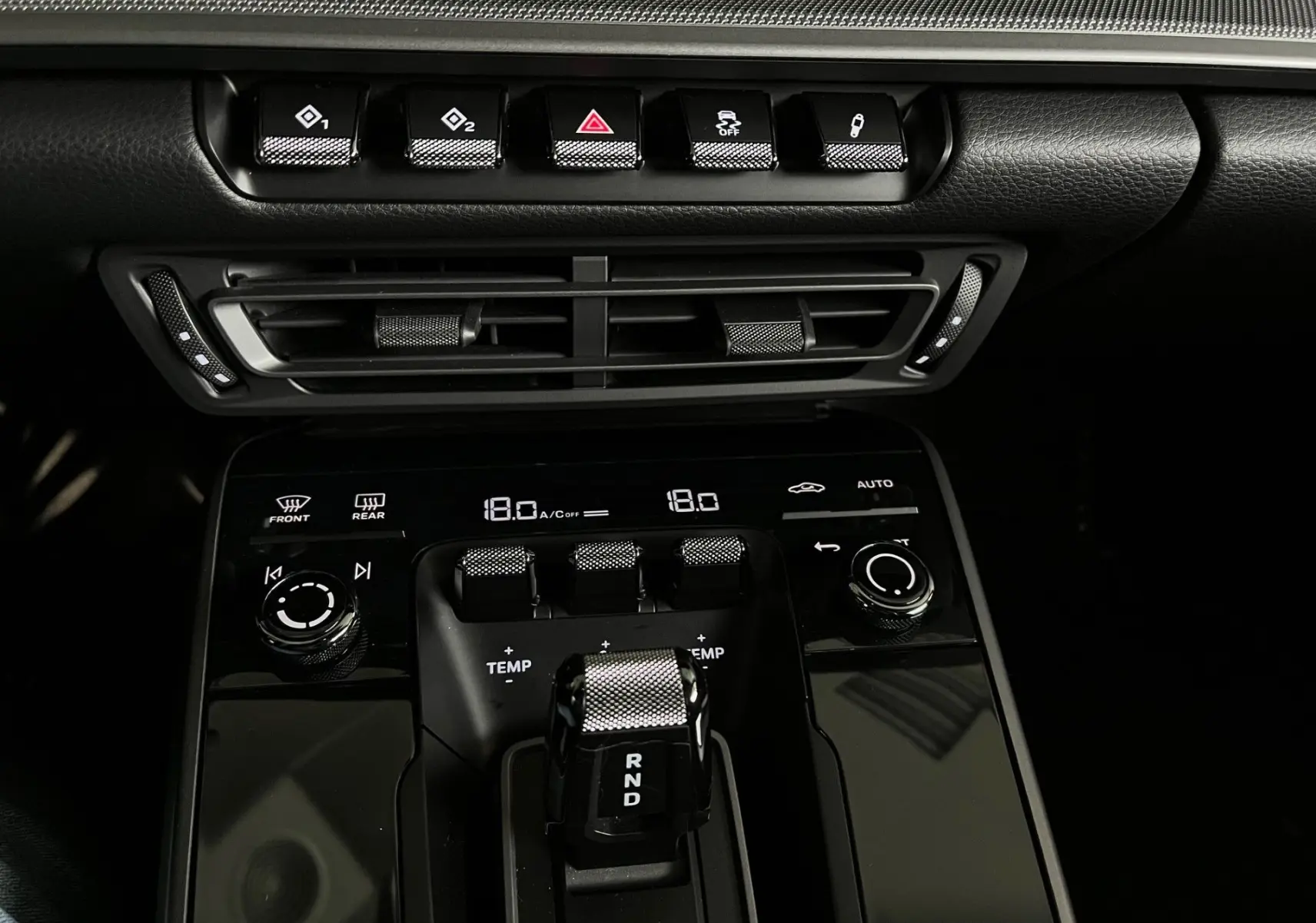 Gros plan sur la console centrale noire brillante de la Porsche 911 992 Carrera S avec levier de vitesses et commandes climatiques.