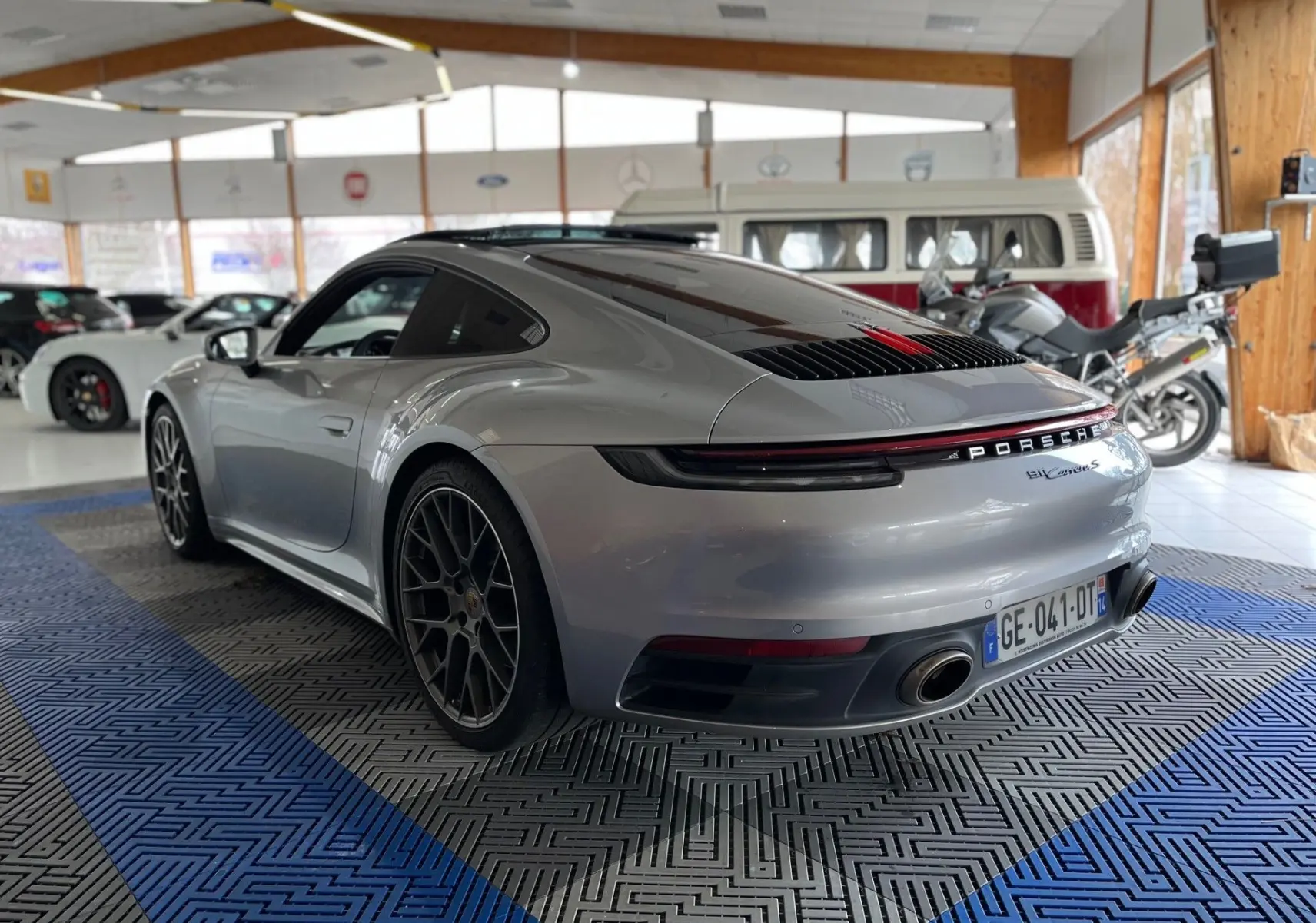 Vue 3/4 arrière droite d'une Porsche 911 Carrera S 2019 argent GT avec jantes RS Spyder en intérieur showroom.