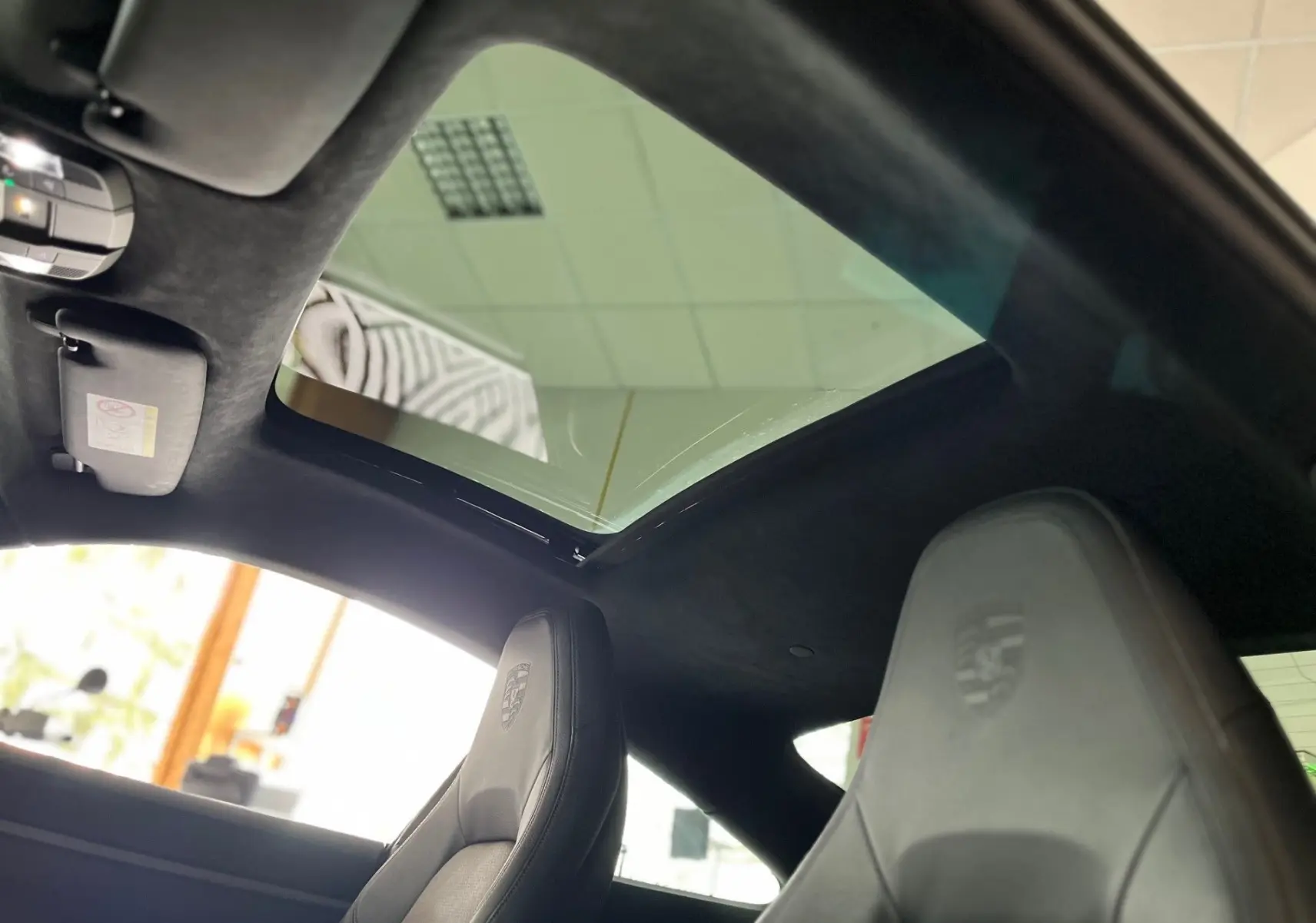 Vue intérieure du toit ouvrant et des sièges avant en cuir noir embossé Porsche d'une 911 Carrera S argent GT 2019