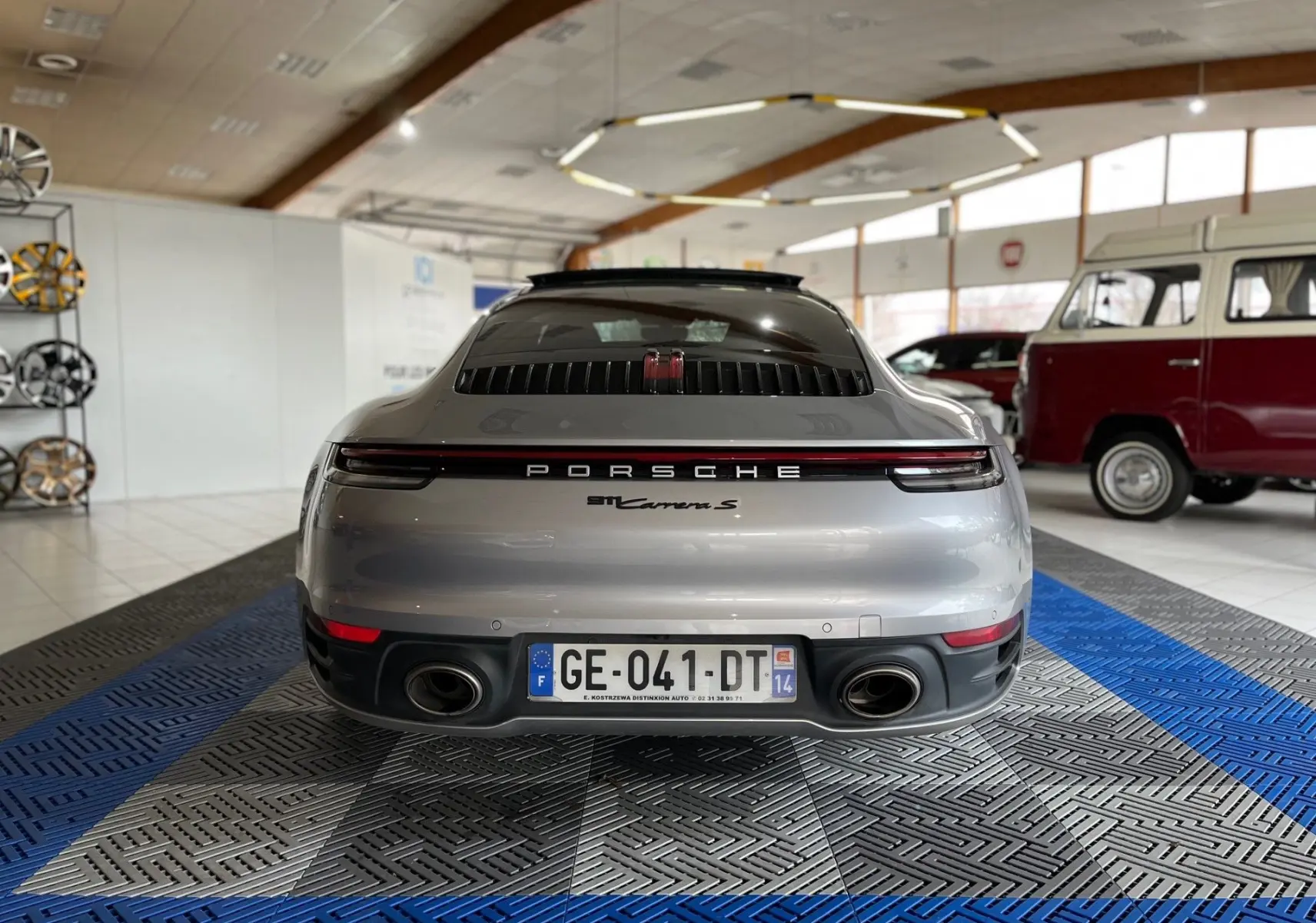 Vue arrière d'une Porsche 911 Carrera S argent GT 2019 avec double sortie d'échappement et feu arrière continu rouge.