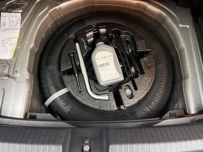 Vue plongeante sur la roue de secours et les outils de bord dans le coffre d'une Volkswagen Polo gris Urano 2021.