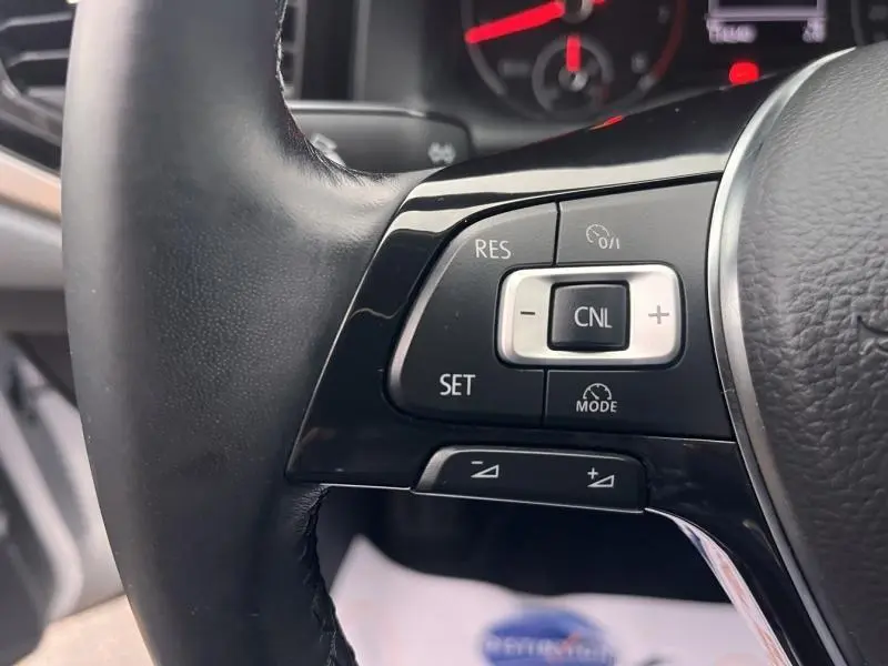 Gros plan sur les commandes multifonctions du volant cuir noir de la Volkswagen Polo gris Urano, côté gauche.