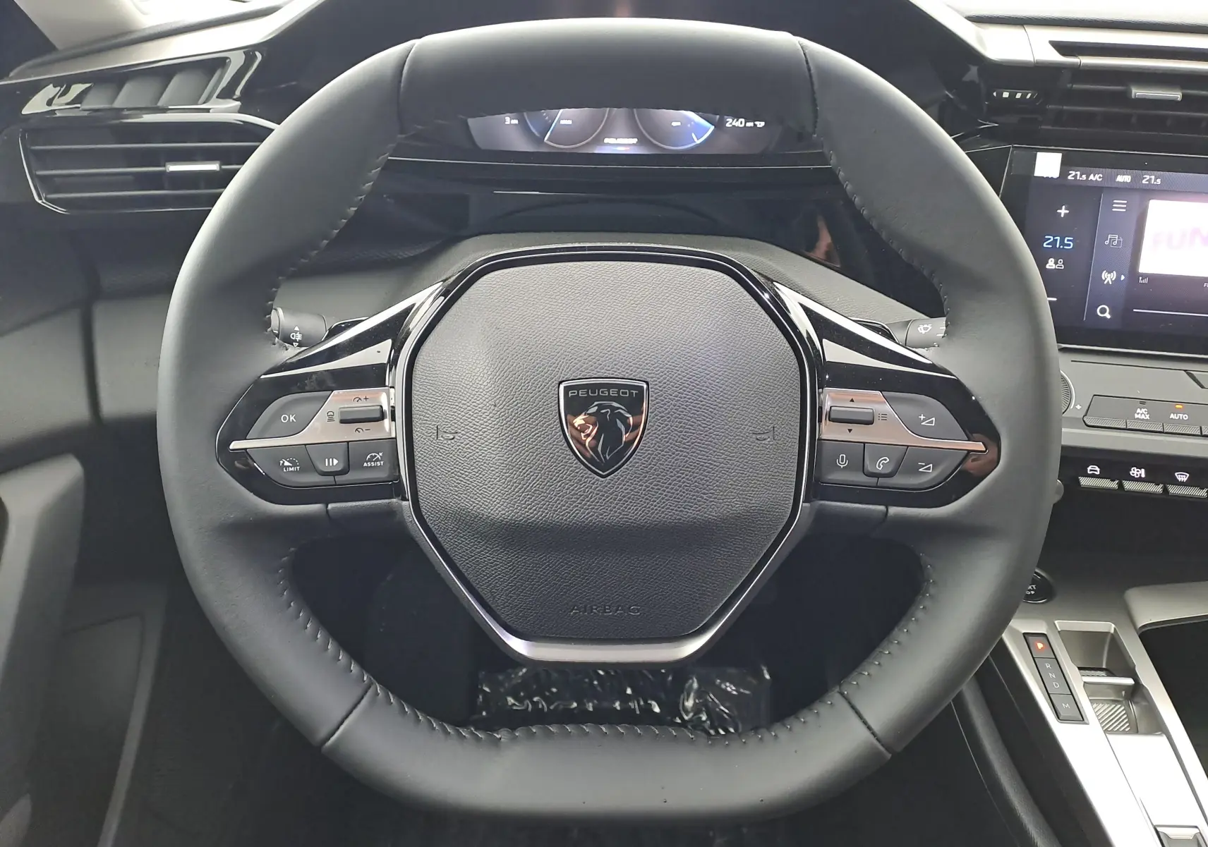 Vue rapprochée du volant noir de la Peugeot 308 2025 avec commandes intégrées et logo lion central.