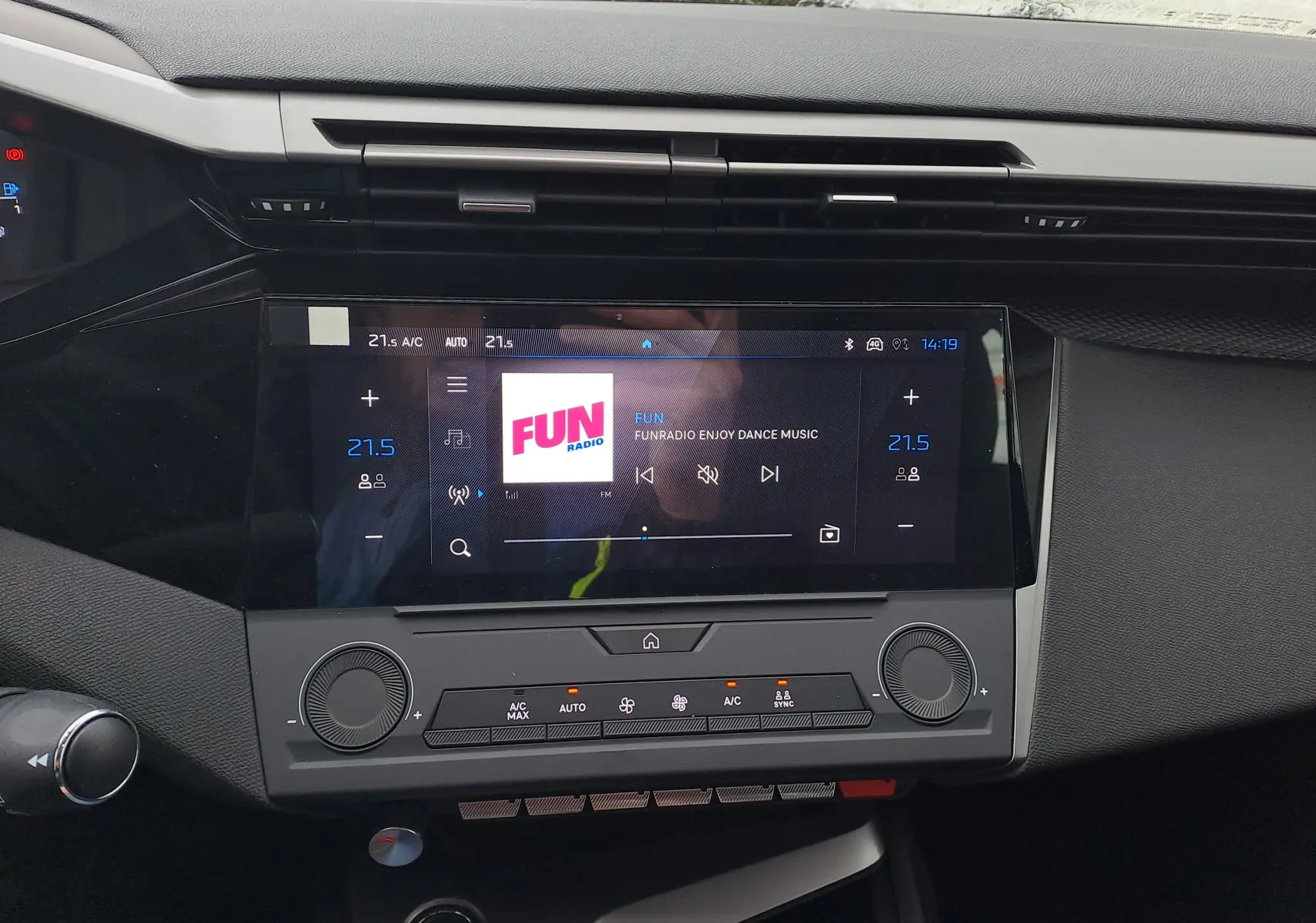 Vue rapprochée de l’écran tactile central et de la console de la Peugeot 308 2025, affichant la radio FUN en mode climatisation à 21,5°C.