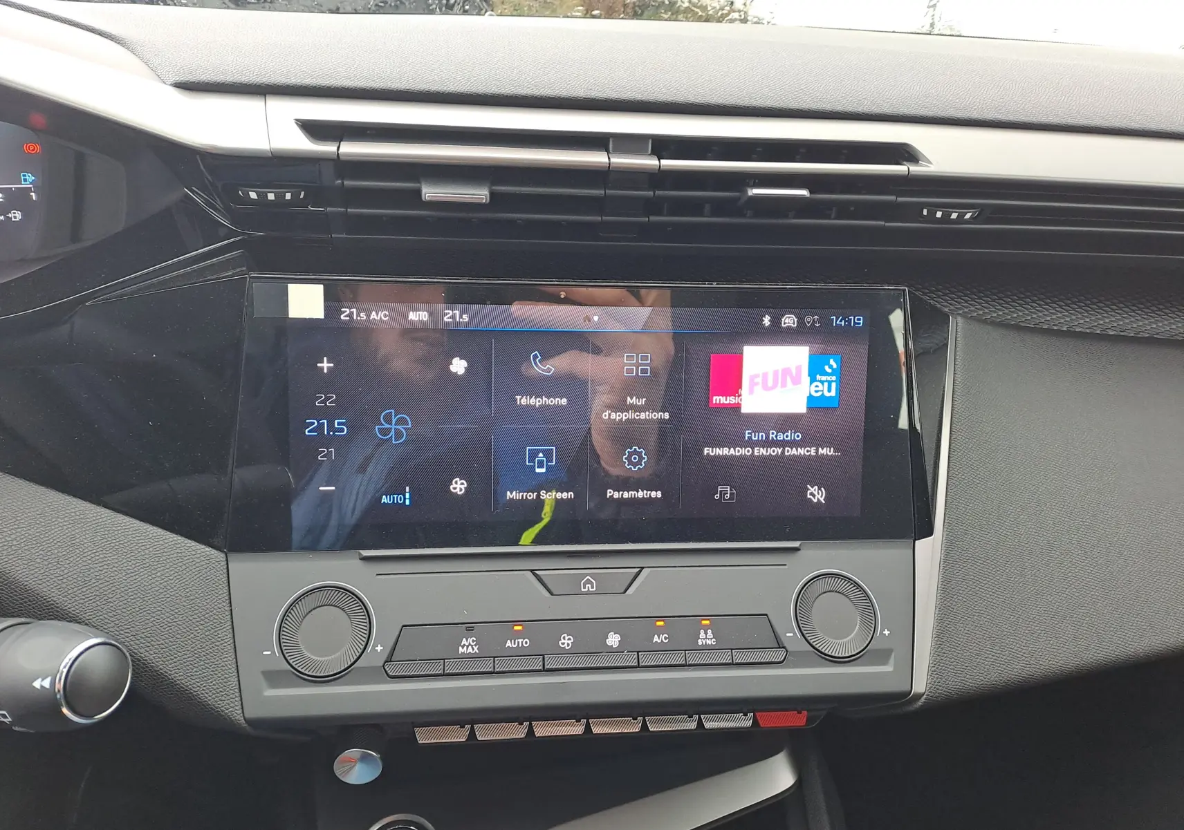 Vue rapprochée de l’écran tactile central et de la console de la Peugeot 308 blanche, affichant les commandes de climatisation et radio.