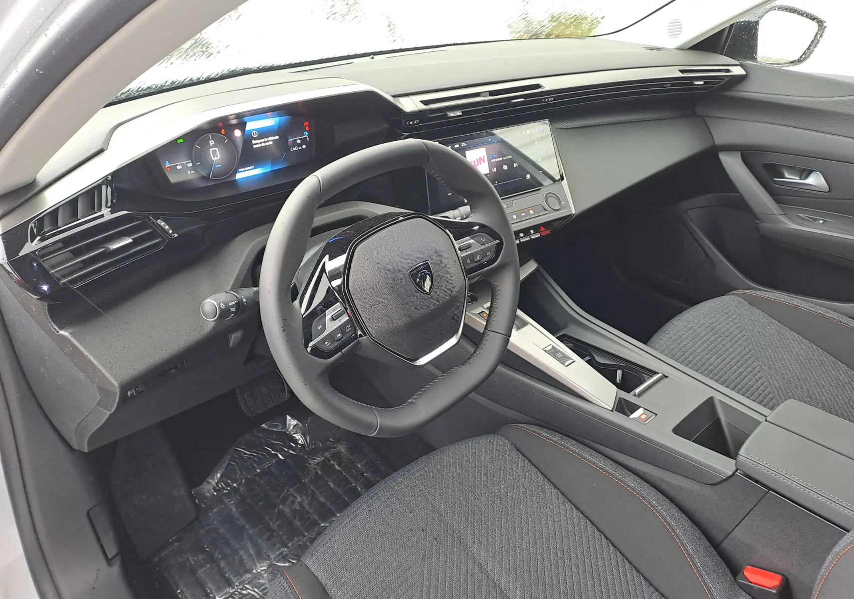 Vue intérieure côté conducteur de la Peugeot 308 2025, tableau de bord moderne avec écran digital et volant compact noir.