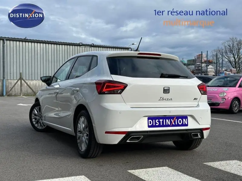 Vue 3/4 arrière d'une SEAT Ibiza 1.0 TSI FR blanche Nevada métallisée avec feux arrière LED et double sortie d'échappement.