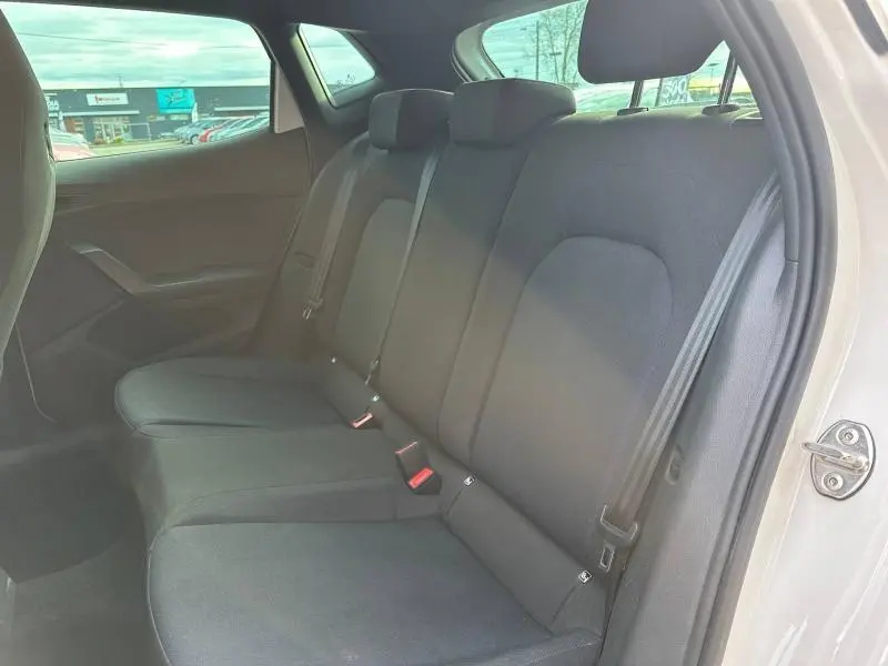 Vue intérieure de la banquette arrière noire du SEAT Ibiza 2025 blanc Nevada, avec ceintures de sécurité visibles côté droit.