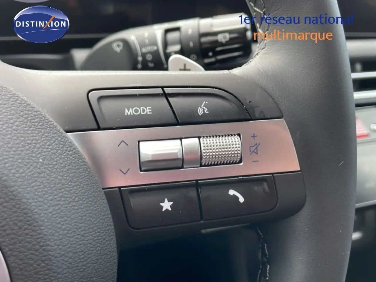 Gros plan sur les commandes gauche du volant cuir noir du Hyundai Tucson blanc Atlas 2026, avec molette et boutons fonctionnels.