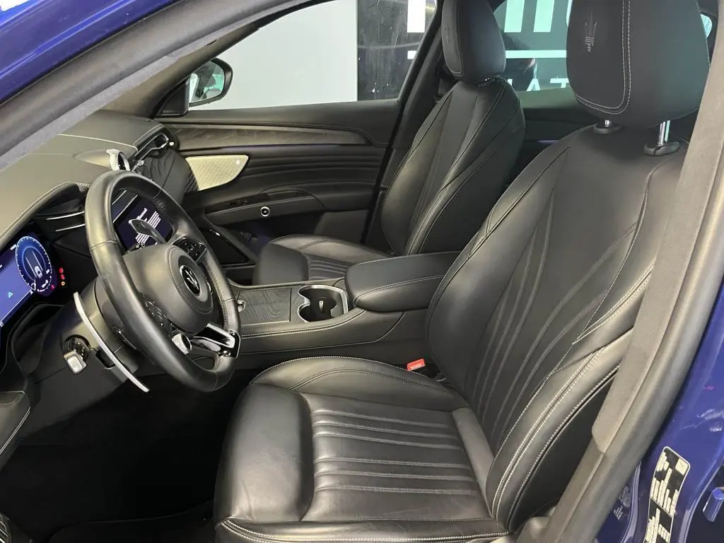 Intérieur avant droit du Maserati Grecale bleu 2022, sièges cuir noirs avec logo Trident brodé sur appuie-tête.